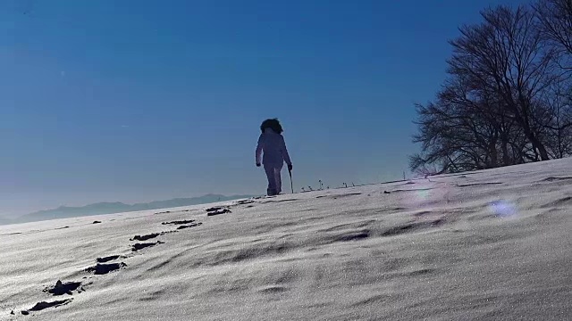 剪影徒步女孩踏在雪地上走向地平线视频素材