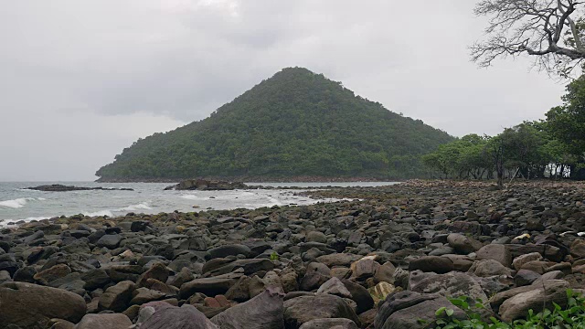 乌云密布的天空下，汹涌的海水涌上岩石嶙峋的海岸线。视频素材