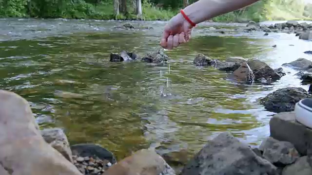 女孩坐在河岸上，摸着水视频素材