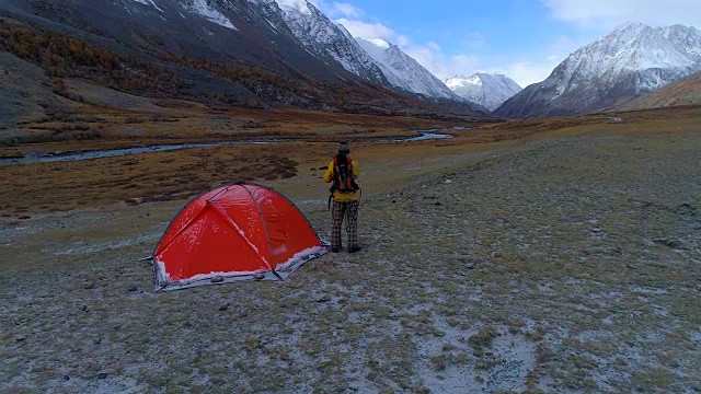 这个男人背着背包在山的背景上徒步旅行。空中FullHD视频素材