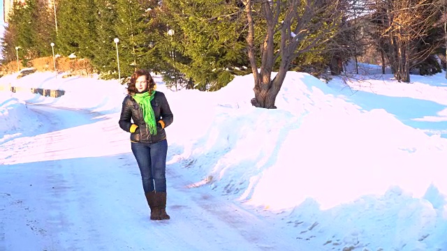 年轻美丽的女孩在户外的雪地上行走。视频素材