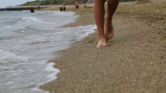 男孩在海滩上的金色沙滩上走着，拿着手机视频素材