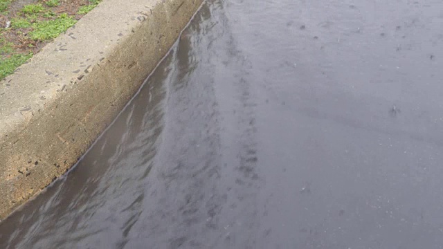 雨点落在街道上，雨滴落在水坑和沥青上。视频素材