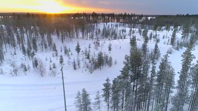 镜头:在金色的夕阳下，汽车行驶在白雪覆盖的道路上，穿过森林荒野视频素材