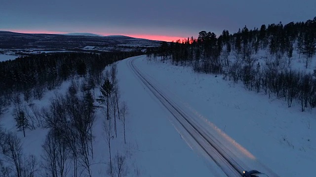 日落时分，一辆汽车在雪山公路上穿过松林视频素材