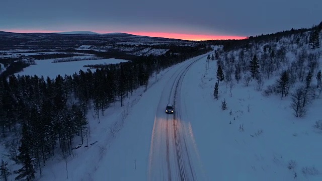 照片:日落时分，一辆汽车在雪山公路上穿过云杉林视频素材