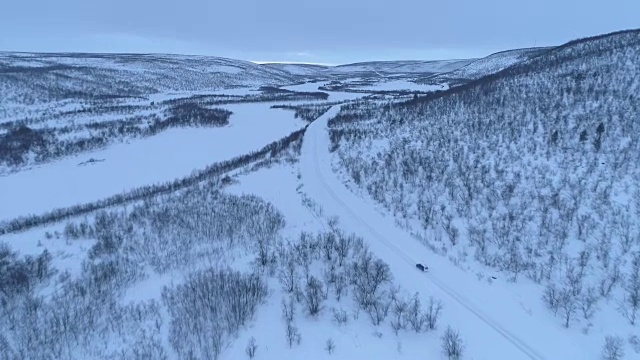 在冬天的早晨，一辆汽车在雪山脚下的高速公路上行驶视频素材