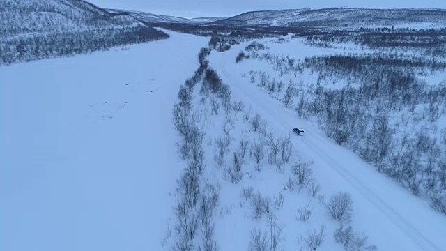 在冬天的早晨，一辆汽车在雪山脚下的高速公路上行驶视频素材