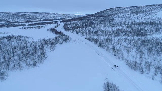 冬天的早晨，汽车在山脚下的雪地上行驶视频素材