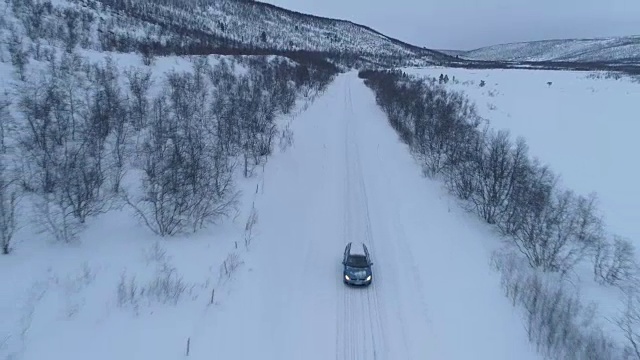 空中特写:汽车在芬兰冬季山谷的冰雪道路上行驶视频素材