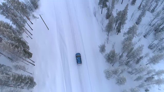 空中俯瞰:汽车行驶在积雪的道路上，穿过寒冷的冬季云杉森林视频素材