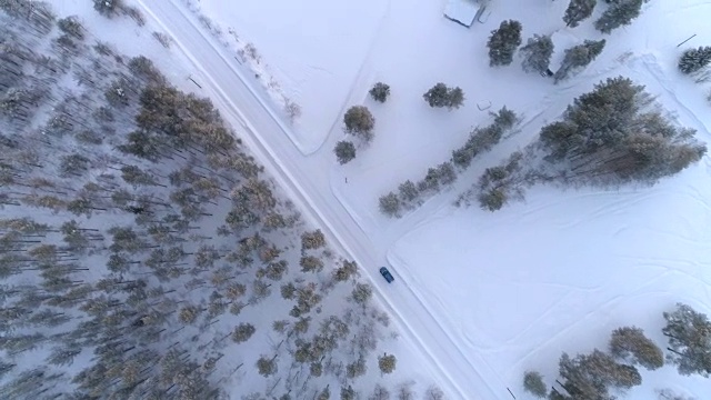 汽车行驶在积雪的道路上，经过一所乡村的房子视频素材