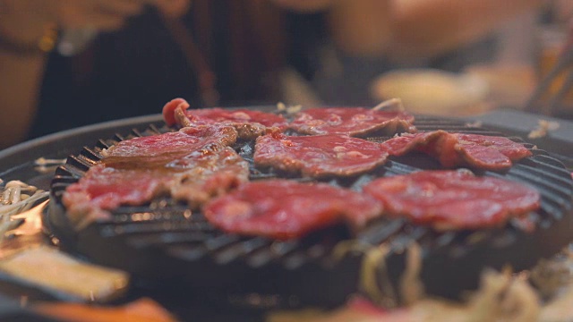 烹饪烧烤，在炉子上的木炭上烤。关闭牛肉烤在日本餐厅。用于烧烤或日式食物的生牛肉片视频素材