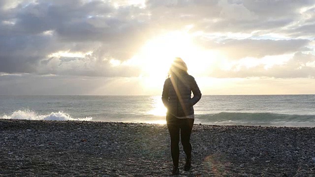 女人走过空旷的海滩，望着大海，望着日出视频素材