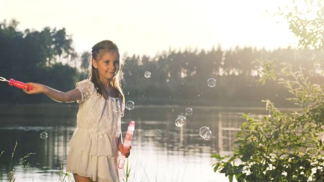 小女孩在森林湖边制造肥皂泡。视频素材