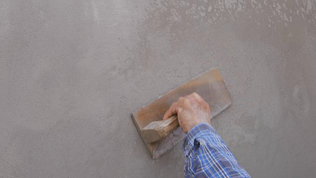 在建筑工地，工人用泥铲完成湿混凝土墙视频素材