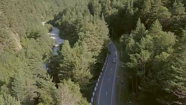 从上面看，美丽的景色沿着绿色的森林到山脉的道路行驶视频素材