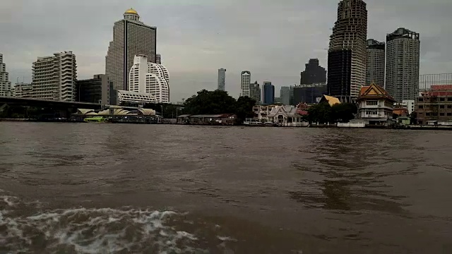 夕阳西下，在曼谷湄南河上的一艘小船上航行。湄南河上有许多豪华酒店和公寓。视频素材