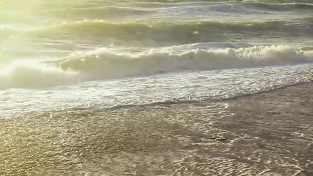 太阳照亮了拍打在沙滩上的海浪视频素材