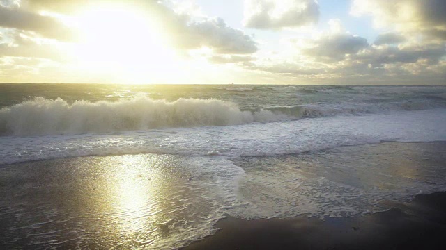 慢慢地，波浪在夕阳中冲击着海岸视频素材