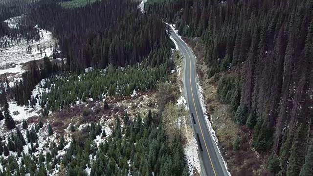 4K航拍:穿越白雪覆盖的森林的道路视频素材