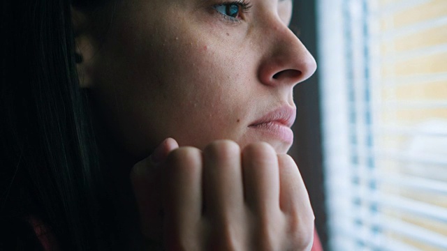 悲伤的女人透过窗户看视频素材