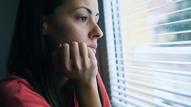 悲伤的女人透过窗户看视频素材