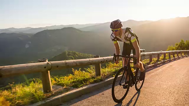 男运动员站在路上骑自行车上山视频素材