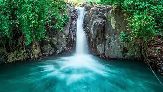 热带瀑布流经茂密的丛林，落入印尼巴厘岛的野生池塘视频素材