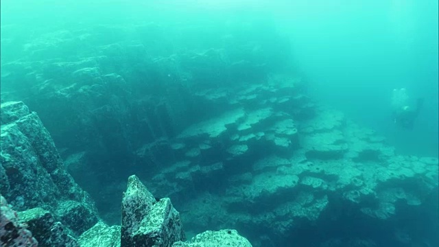 水下拍摄;在日本北海道沙戈滩半岛海岸附近的柱状接头附近游泳的潜水员。视频素材