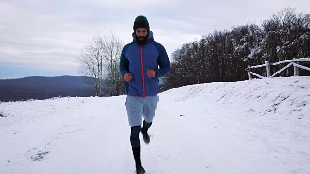 敬业的男运动员在雪地上慢跑。视频素材