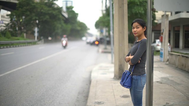 年轻的亚洲女人站在公共汽车站视频素材