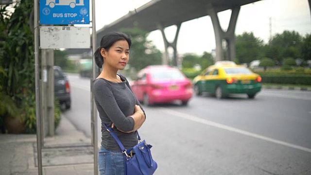 年轻的亚洲女子在曼谷的公共汽车站等车视频素材