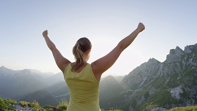 近镜头光晕:胜利的女人在令人惊叹的山顶上伸出手臂。视频素材