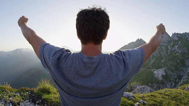 近距离镜头光晕:年轻的徒步旅行者举起手臂庆祝登山。视频素材