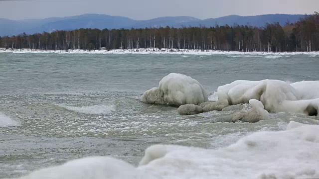 覆盖着冰的石头被海浪冲蚀了视频素材