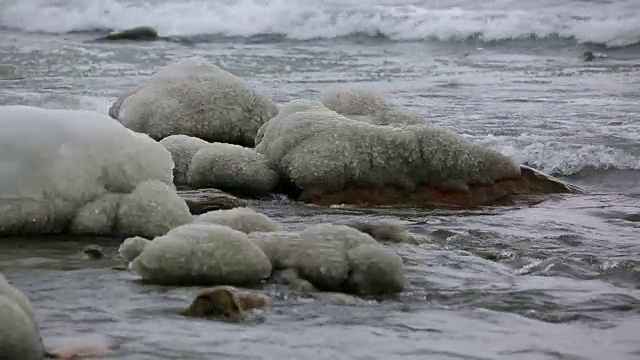 大浪打在被冰覆盖的石头上视频素材