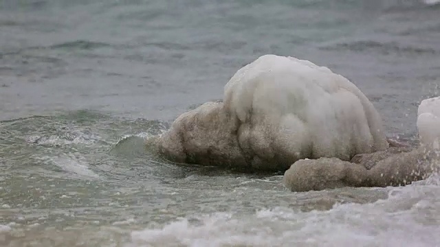 覆盖着冰的石头被海浪冲蚀了视频素材