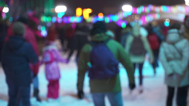 冬季运动概念。晚上在城市溜冰场的人群。一大群开心的人在滑冰。雪下降。圣诞天模糊。运动和好心情的概念。家庭和幸福的夫妇滑冰视频素材