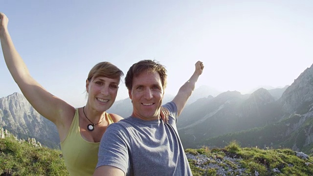 肖像:一对兴高采烈的徒步旅行者在阳光明媚的日子庆祝征服高山视频素材