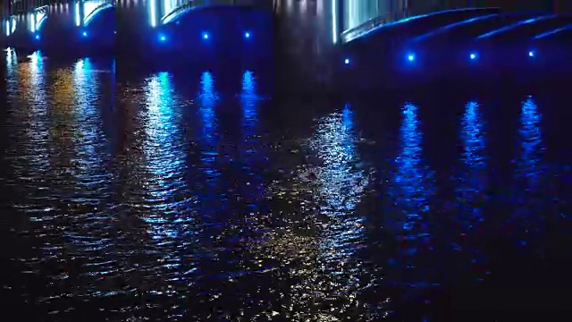 美丽的历史桥横跨欧洲城市的河流在夜晚倾斜。视频素材