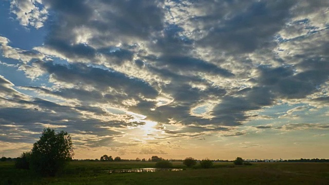 在夕阳的余晖中，美丽的云彩映衬在绿色的草地上。时间流逝视频1920 × 1080视频素材