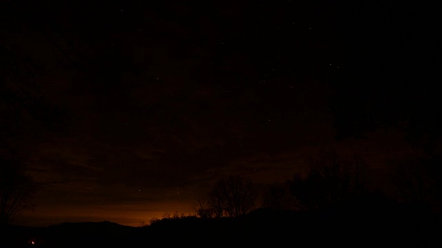 夜间的时间流逝的云移动在山上与星星逆时针旋转视频素材