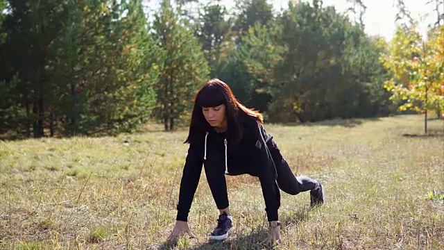 一位穿着运动服的女士在慢跑穿过公园之前暖暖她的腿部肌肉视频素材