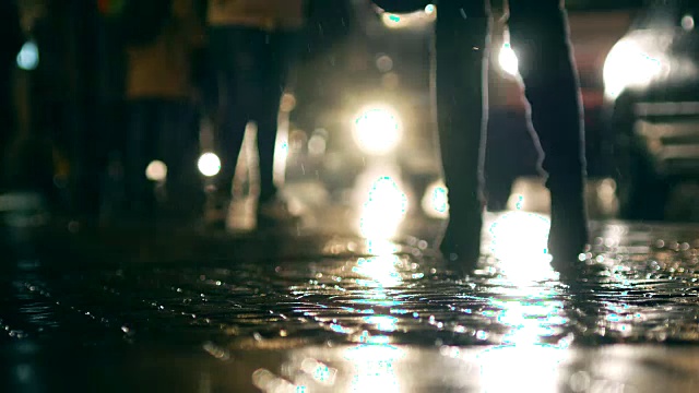 下雨的夜晚，人们走在潮湿的人行道上的影子视频素材