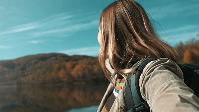 女人拿着相机，拍着，指着湖面视频素材