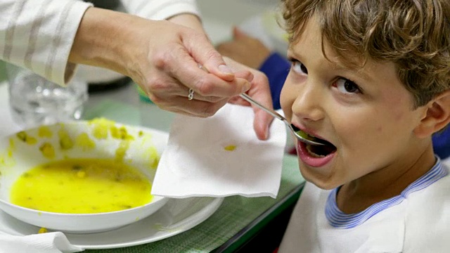 快乐英俊的孩子在4K晚餐时间被喂健康的蔬菜汤视频素材