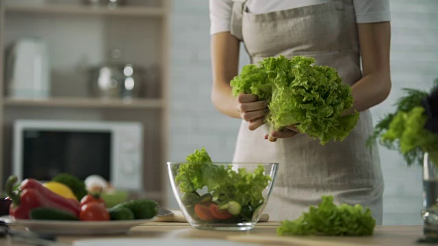 女厨师准备蔬菜沙拉，把它撕烂，放进玻璃碗里，节食视频素材