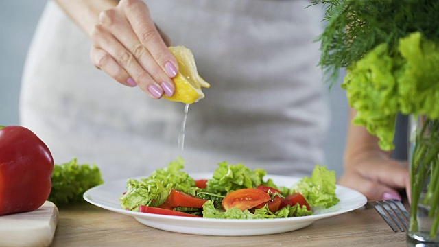 家庭主妇在蔬菜沙拉上洒上柠檬汁，食用富含维生素的食物视频素材