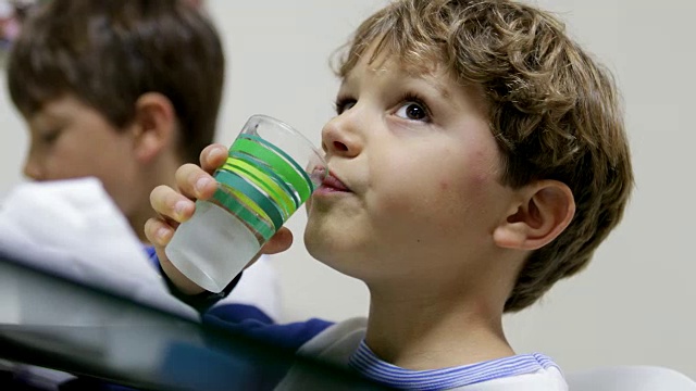 帅气的小男孩在晚餐时间喝一杯水的瞬间。儿童饮水随意在4K视频素材
